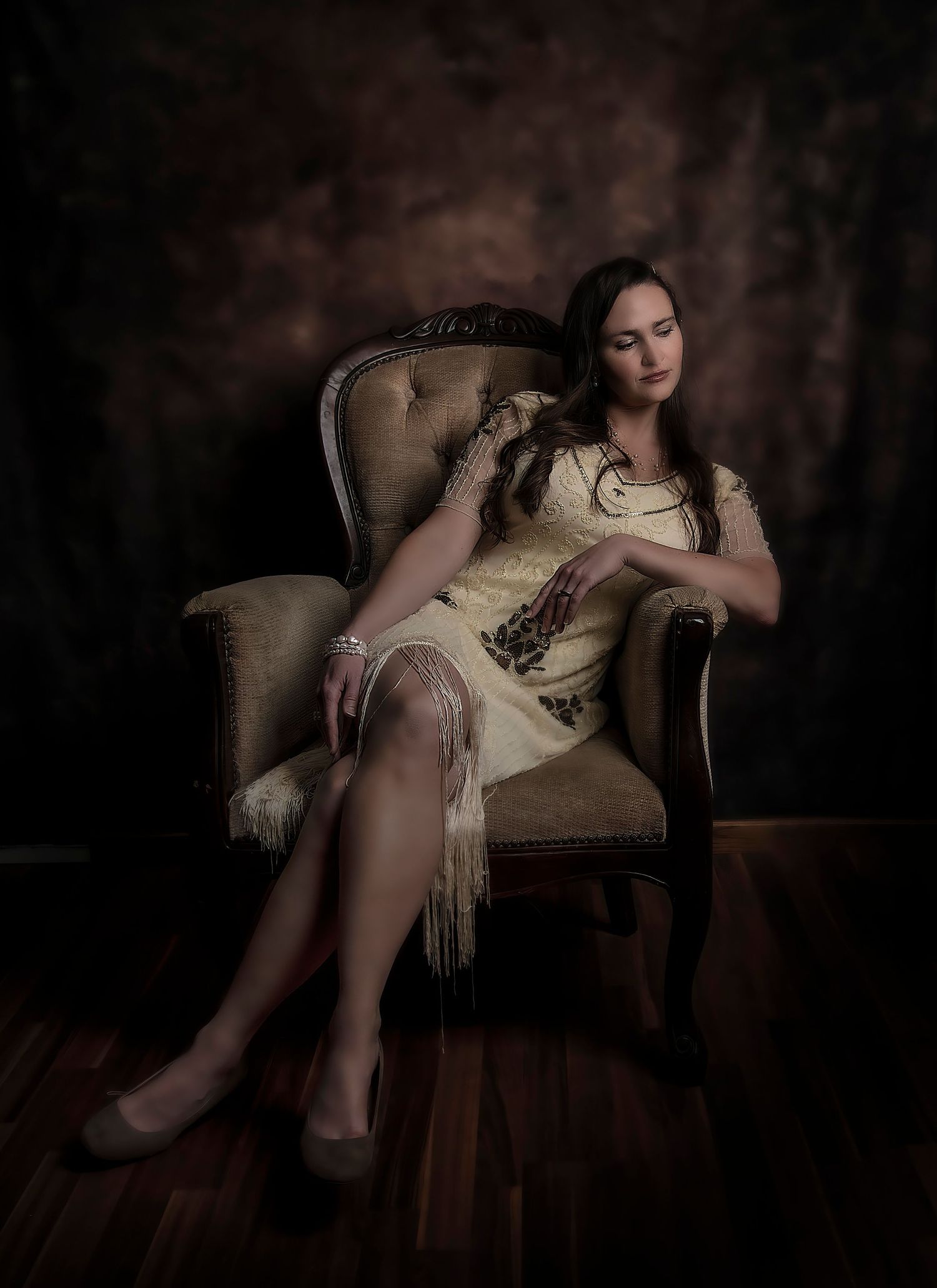 Vintage-style portrait in beige dress seated in antique chair.