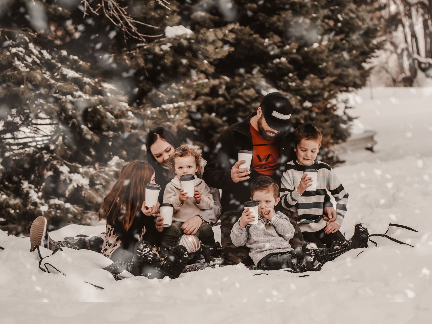 A joyful winter sledding scene in the snow with everyone bundled up in warm clothes.