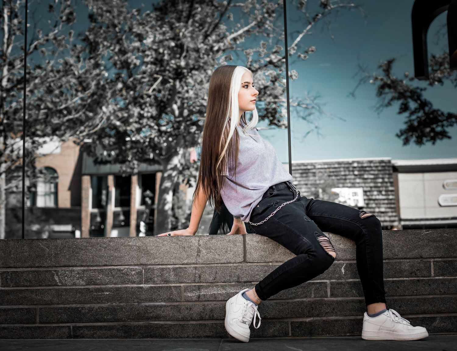 Person in casual attire sitting on concrete steps in an artistic urban photo.