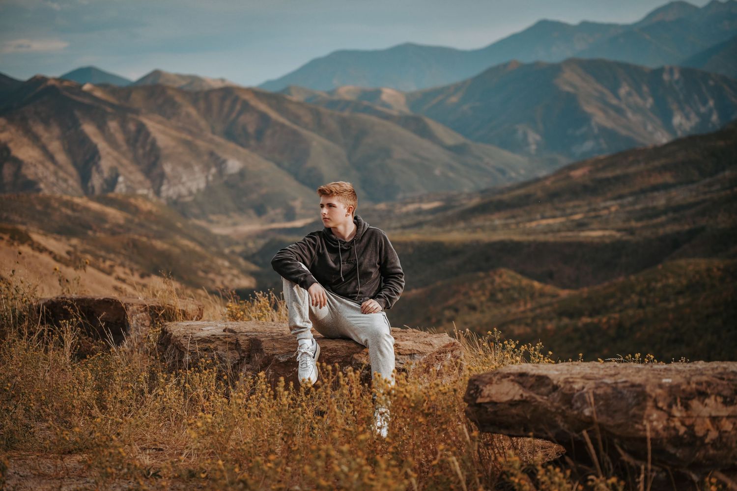 Elegant couple poses in formal attire against scenic mountain backdrop during golden hour wedding photoshoot.