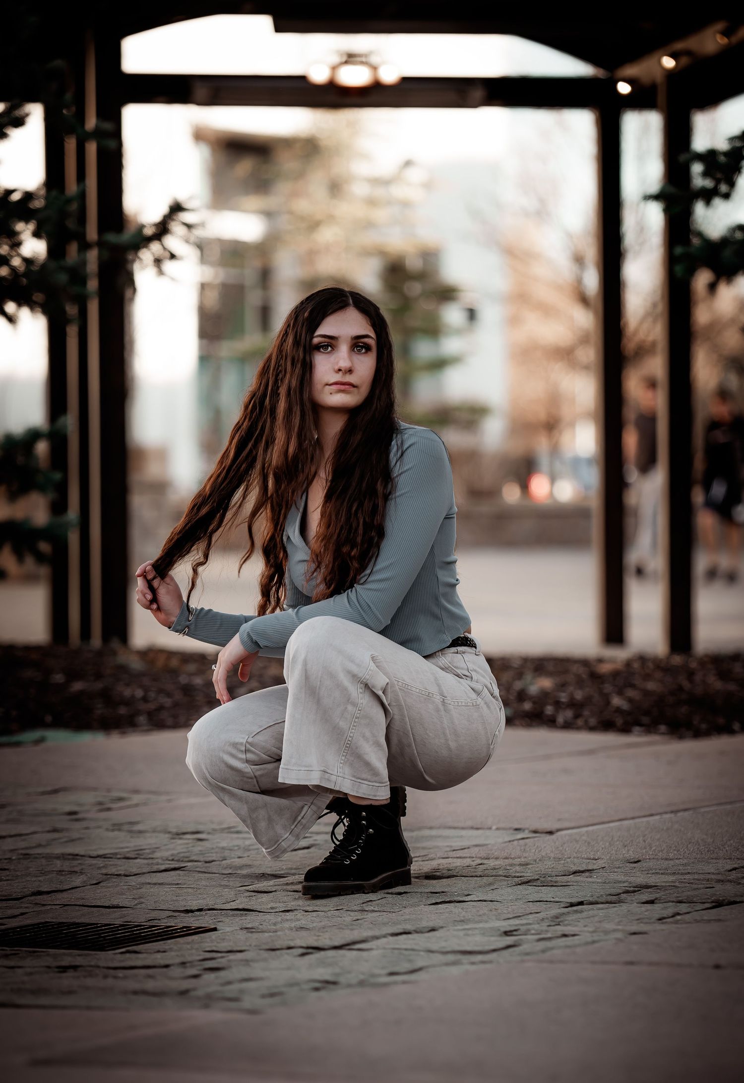 Artistic portrait in urban setting with glass bus shelter and moody lighting.