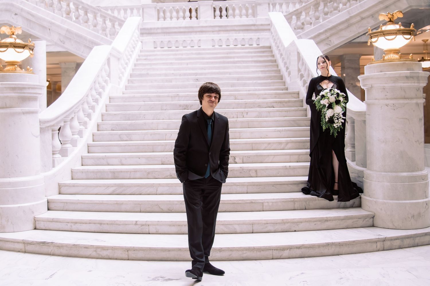 A line of figures stands in formal attire along an ornate white marble staircase at what appears to be a special event.