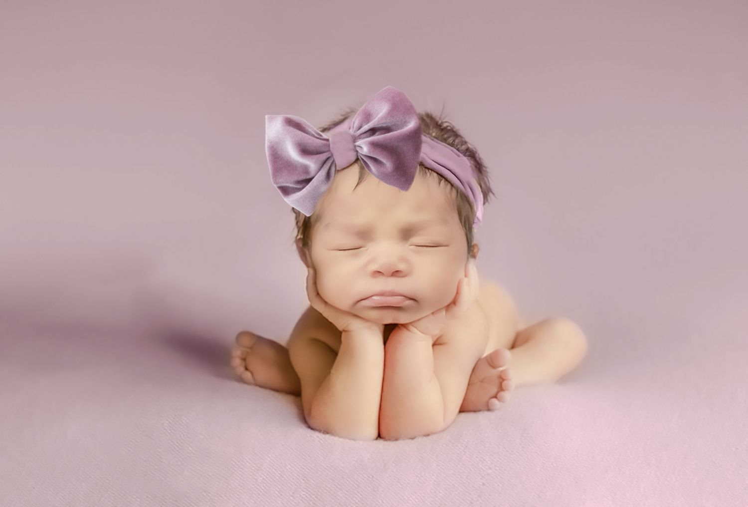 Delicate pink newborn photography setup with soft lighting and accessories.