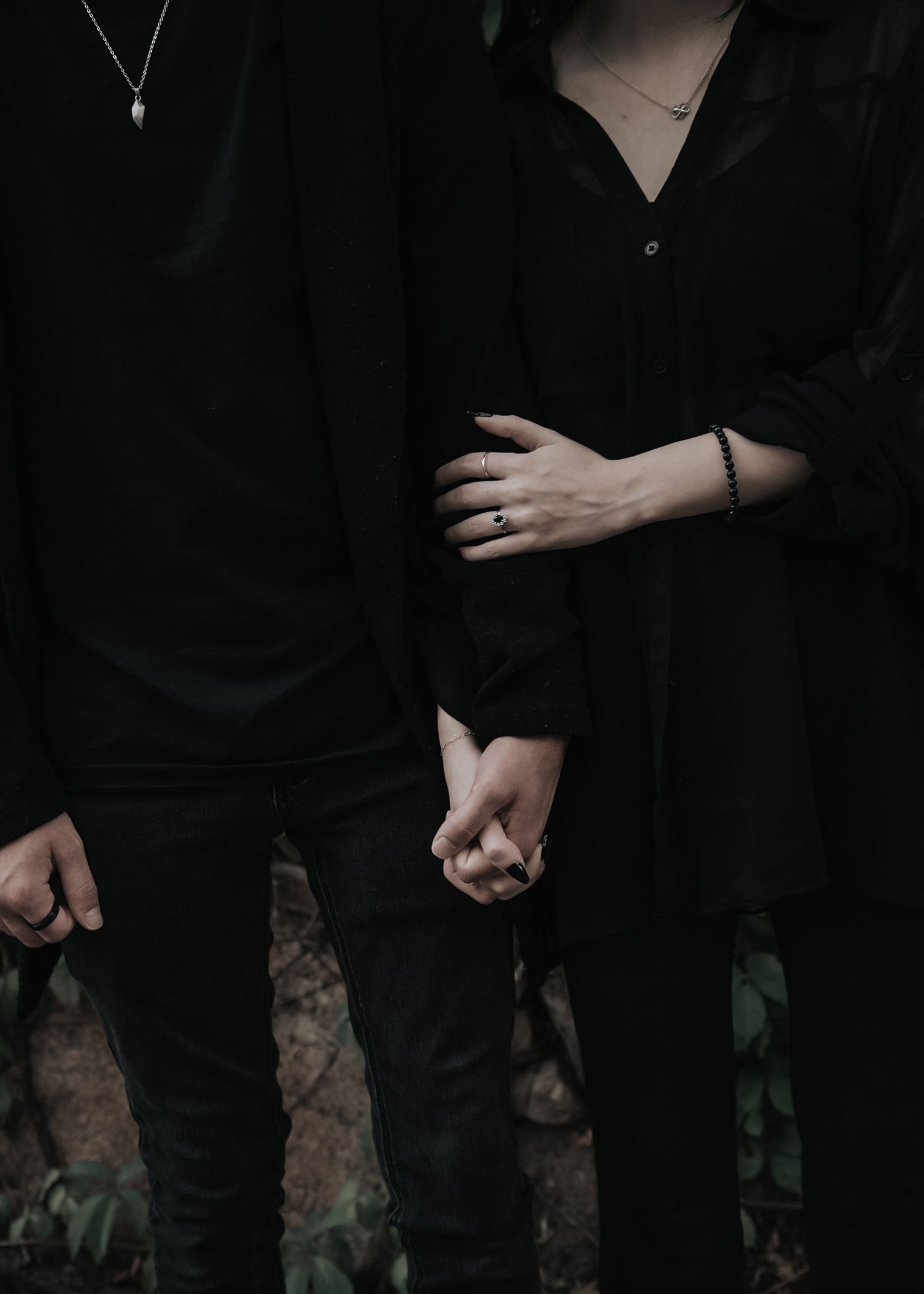 Row of people wearing black clothes standing together against dark background.