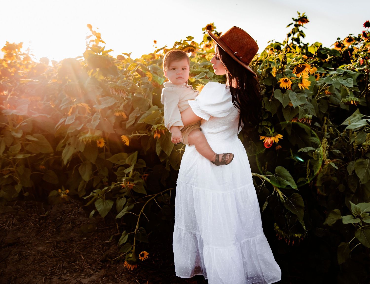 A tender moment captured in a sunlit sunflower field at golden hour.