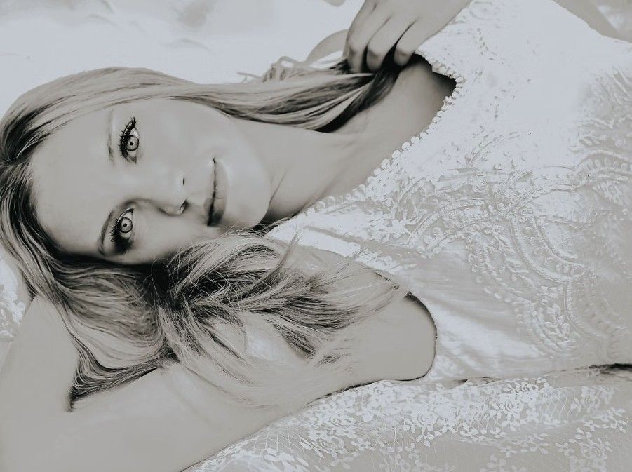 Four black and white photos show a figure in white lace lying down in artistic portrait poses.