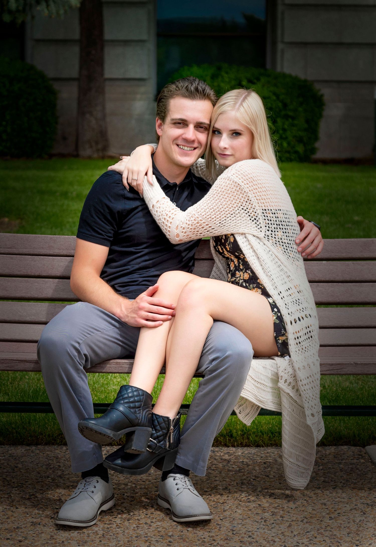 Couple in casual wear embracing on a wooden bench outdoors.