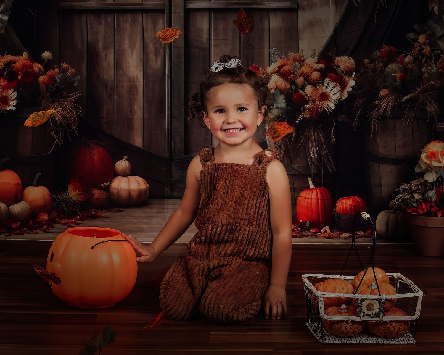 Fall harvest scene with pumpkins, wooden backdrop and autumn floral decorations.