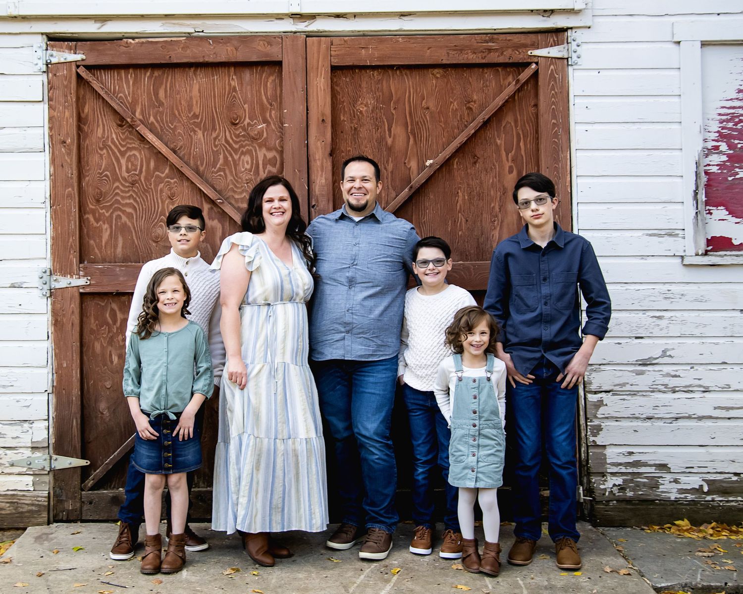 Family group standing together in front of rustic wooden barn doors.