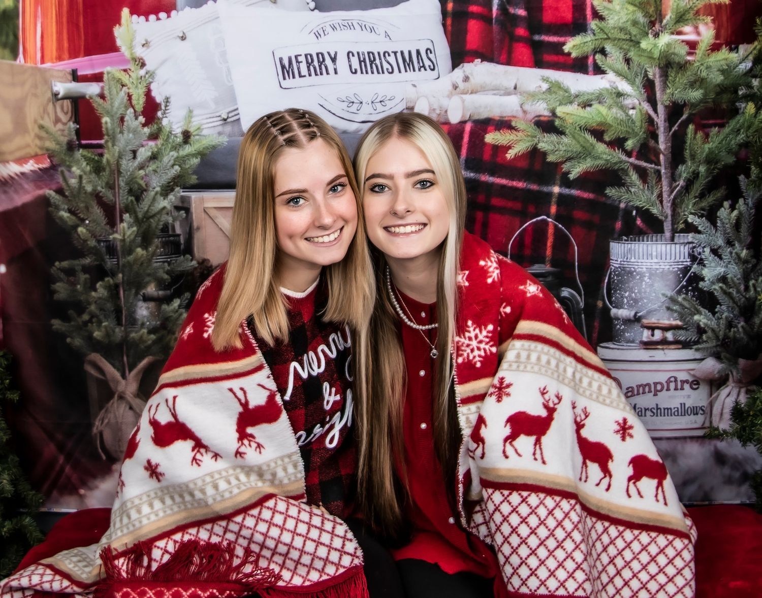 People wearing matching red and white Nordic Christmas sweaters pose together in front of festive holiday decorations.