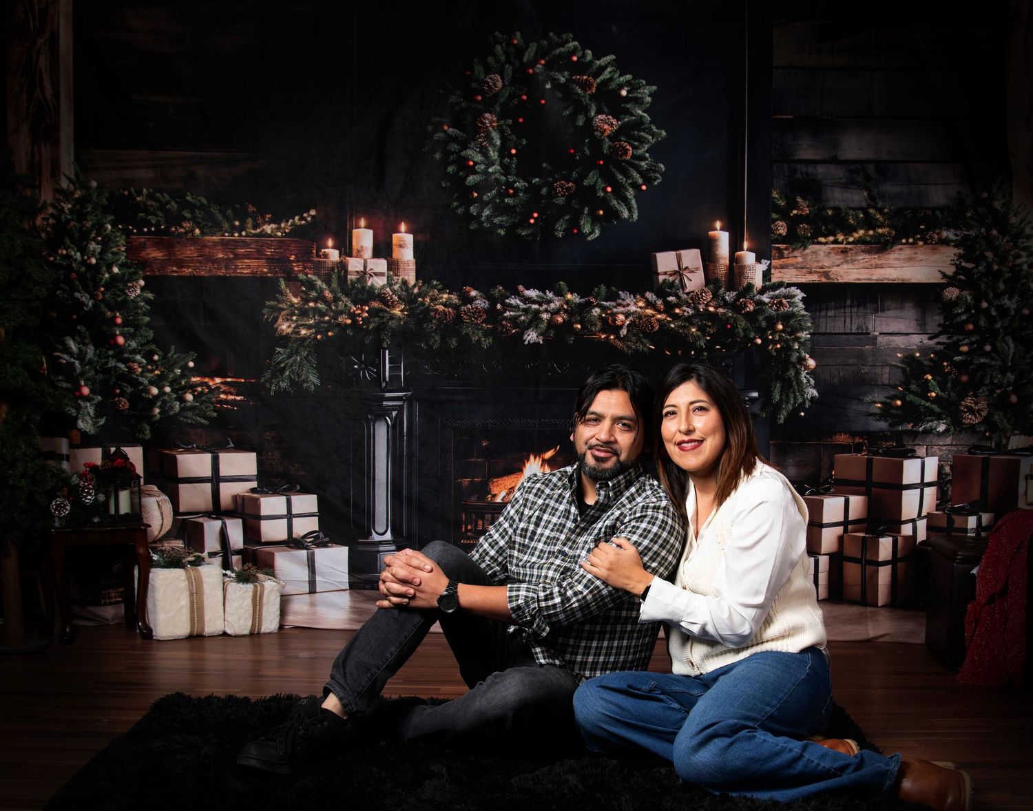 Couple sitting on floor surrounded by white candles in romantic evening setting.