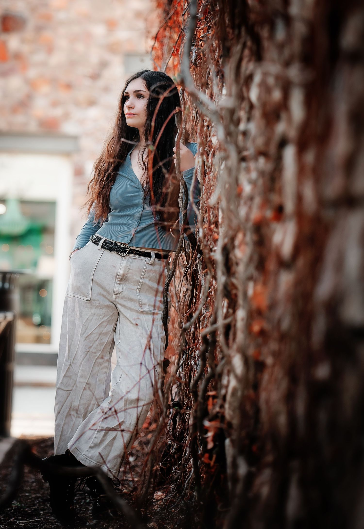 Fashion portrait against brick wall with ivy featuring casual outfit and natural styling.