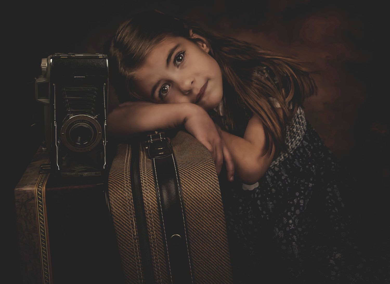 Moody portrait with vintage suitcase and camera in dark atmospheric lighting.