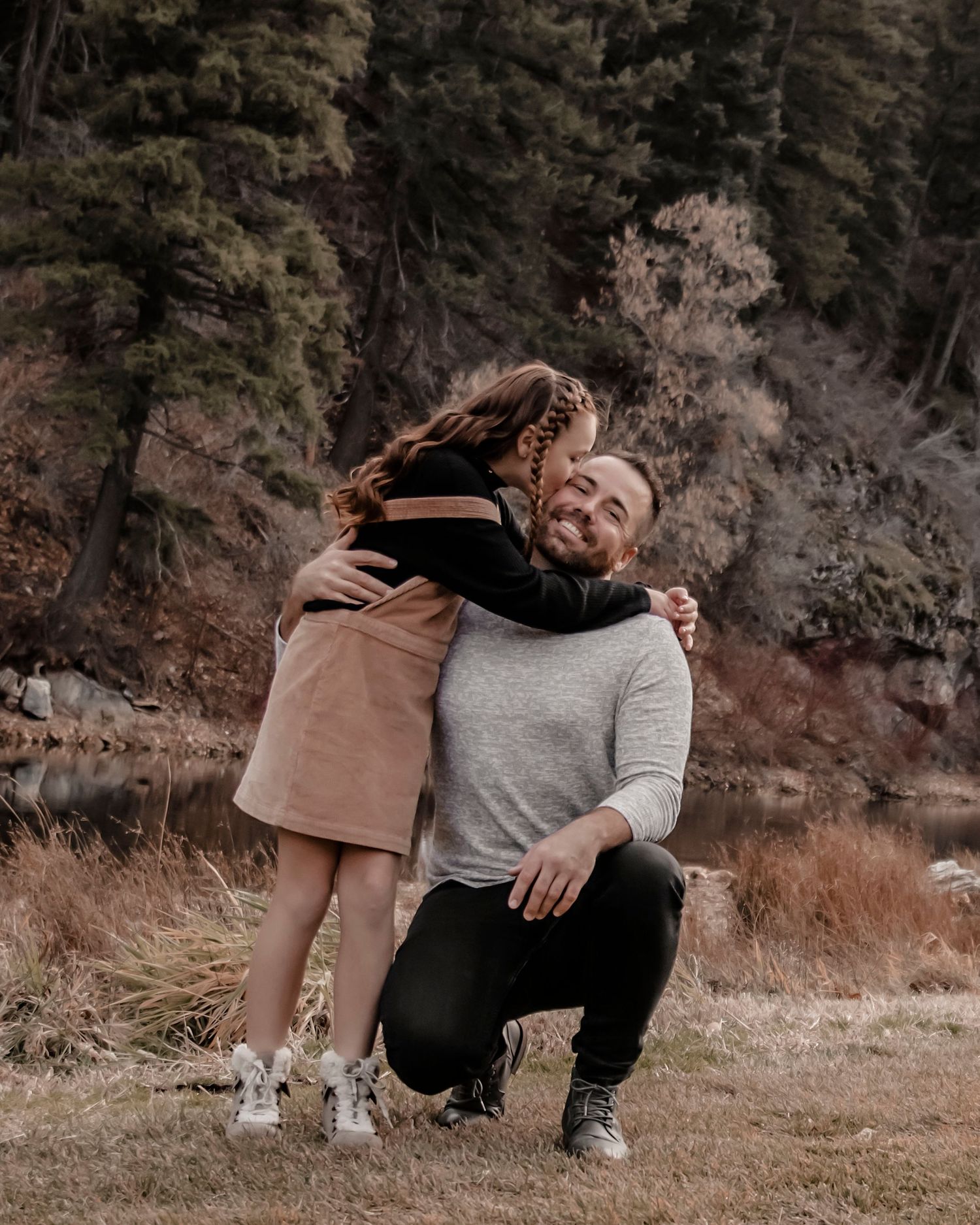 A heartwarming embrace between two people in casual attire against an autumn forest backdrop.