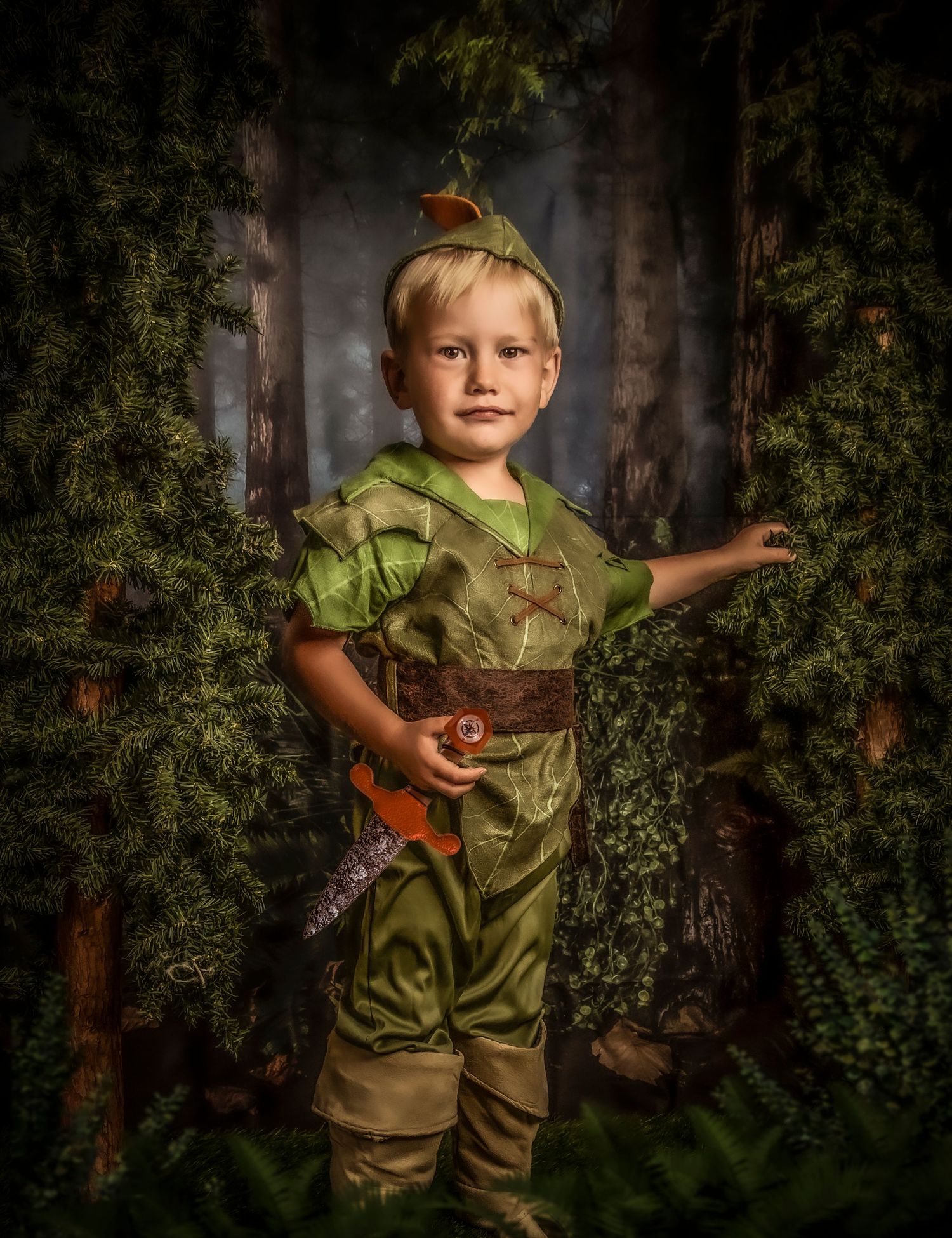 Child dressed as Peter Pan poses in a magical forest setting with woodland props.