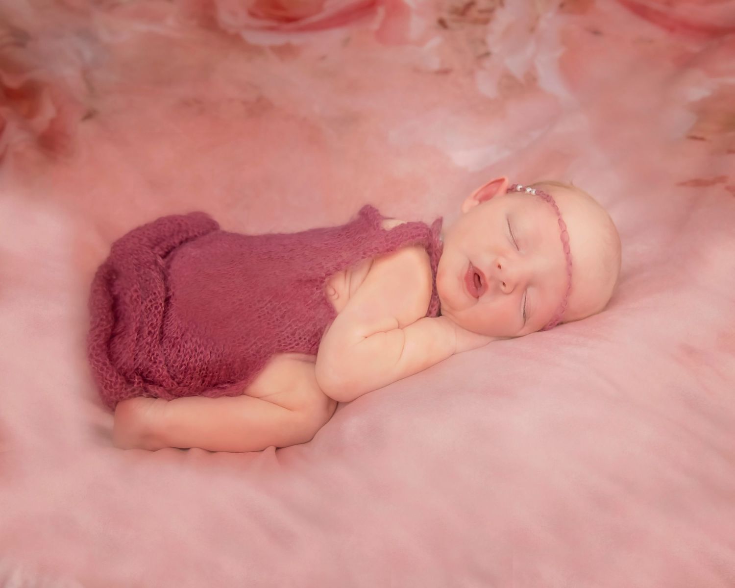 Soft pink newborn photography setup with delicate lighting and textures.