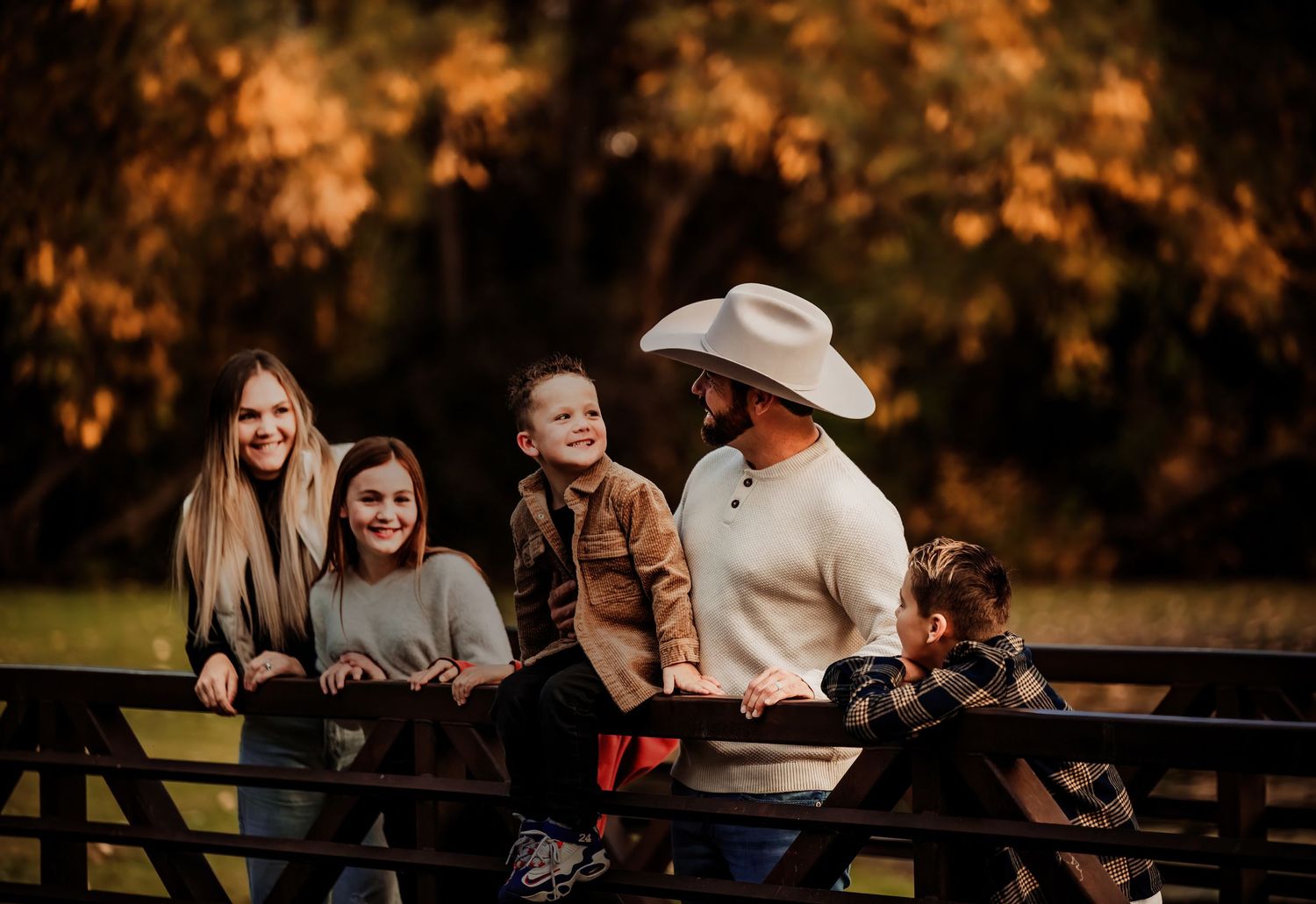 A candid family moment captured on a rustic bridge during golden hour.