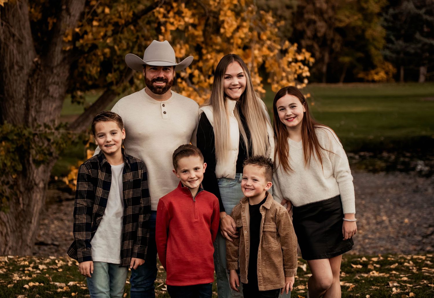 A warm family portrait captured in autumn with fall foliage in the background.
