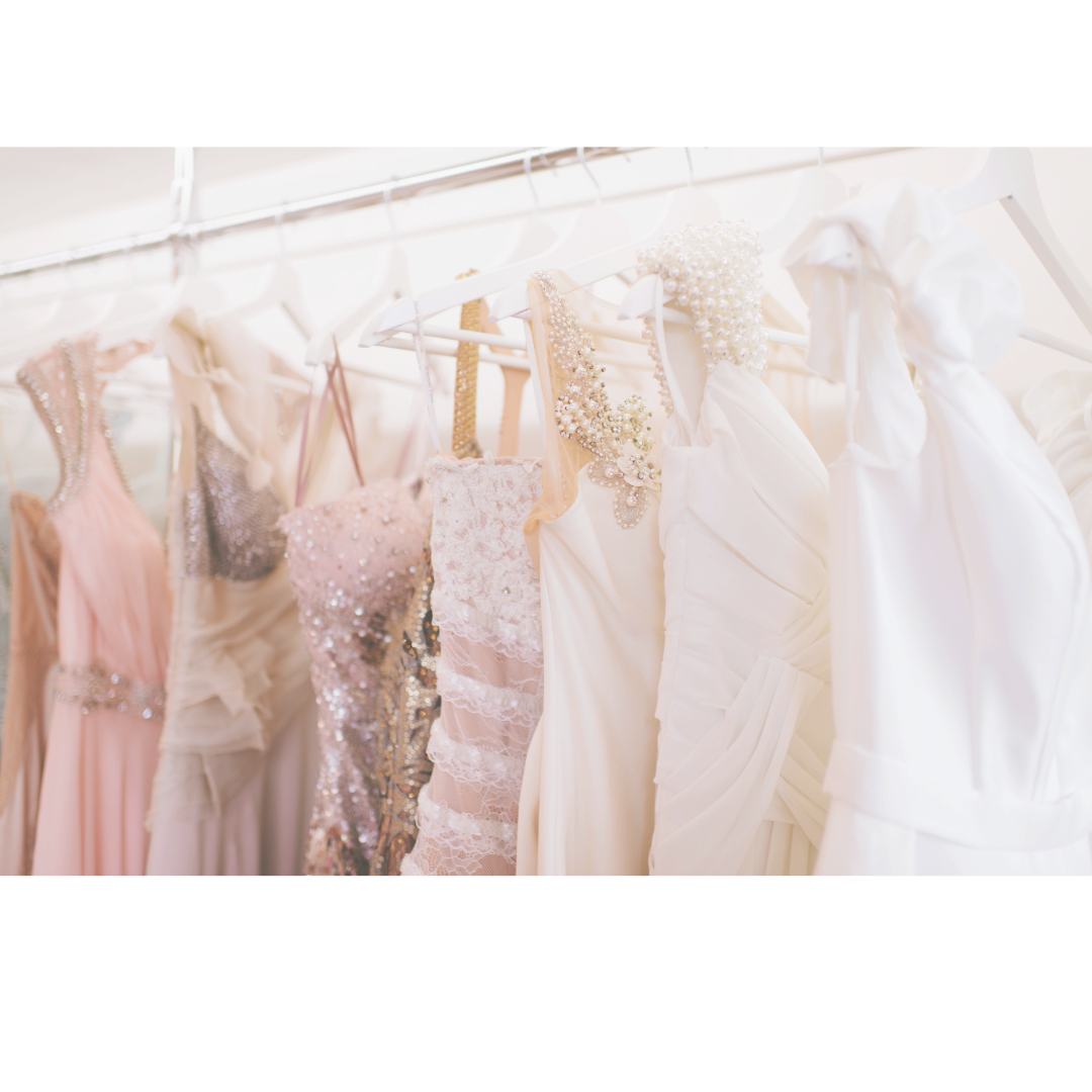 A collection of pastel pink and white dresses hanging on display in a photography studio.