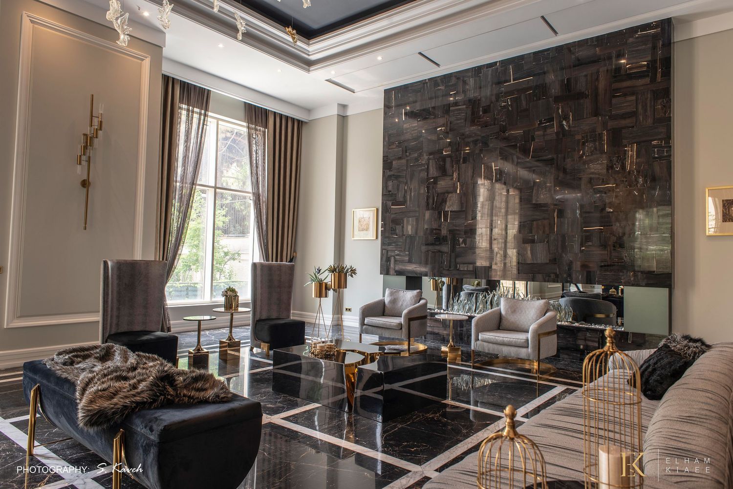 Luxury living room with dark marble floors, gold accents, velvet chairs, and a dramatic stone feature wall.