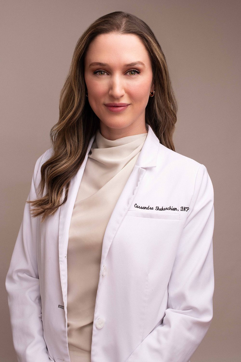 Female healthcare professional in white lab coat with name tag, professional headshot portrait.