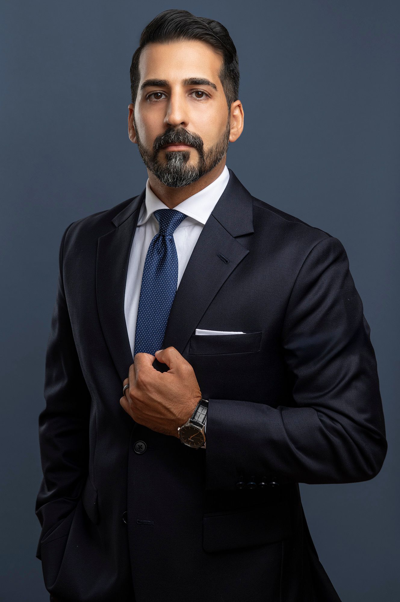 Professional man in dark suit and blue tie, formal business headshot portrait.