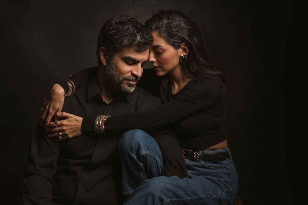 Affectionate couple in casual dark clothing sharing intimate moment in studio portrait.