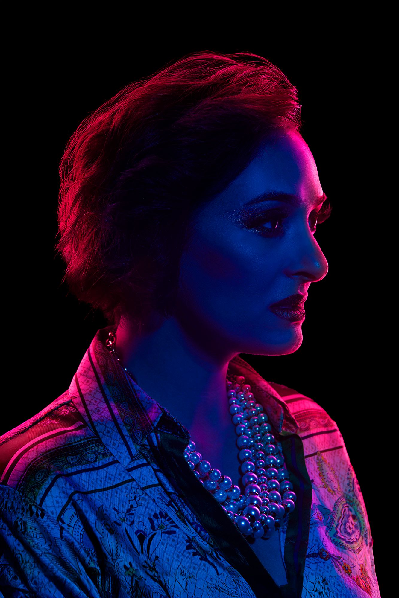 Side profile of woman with short hair in neon red and blue lighting.