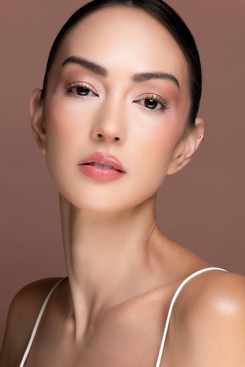 Close-up beauty portrait of Asian woman with natural makeup on brown background.