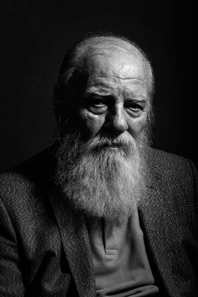 Black and white dramatic portrait of an elderly man with a long white beard and weathered face.