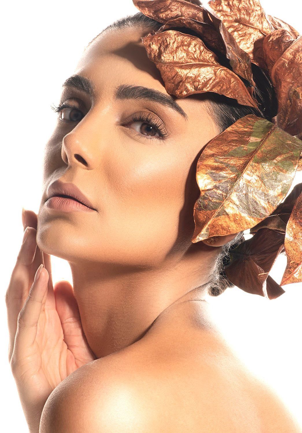 Close-up beauty portrait of woman with golden autumn leaves headdress on white background.