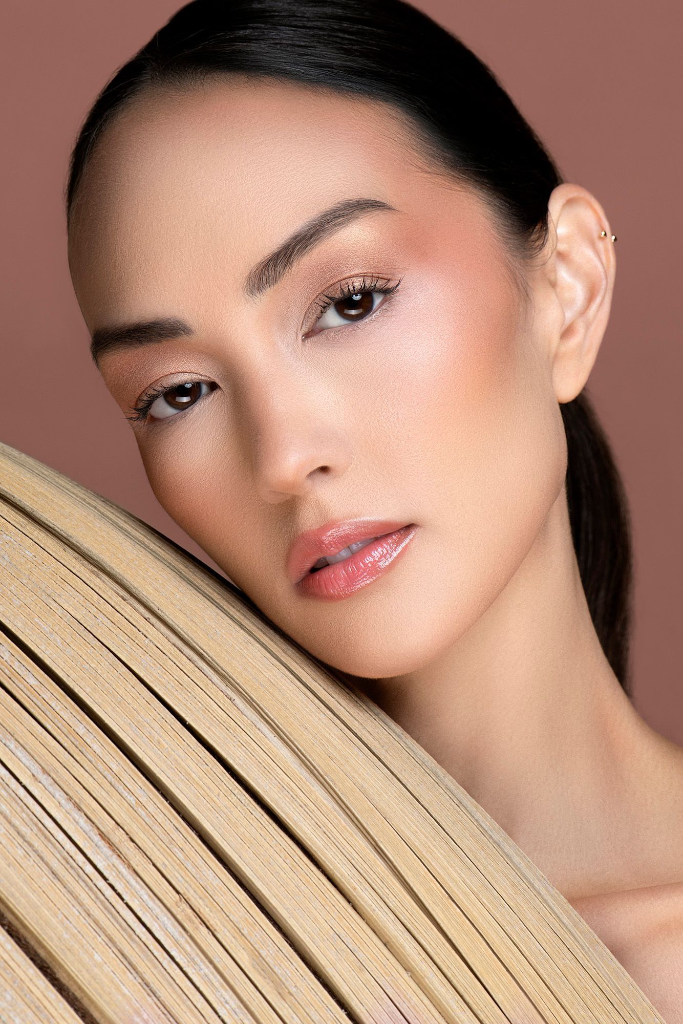 Close-up beauty portrait of Asian woman with natural makeup resting on wooden texture.