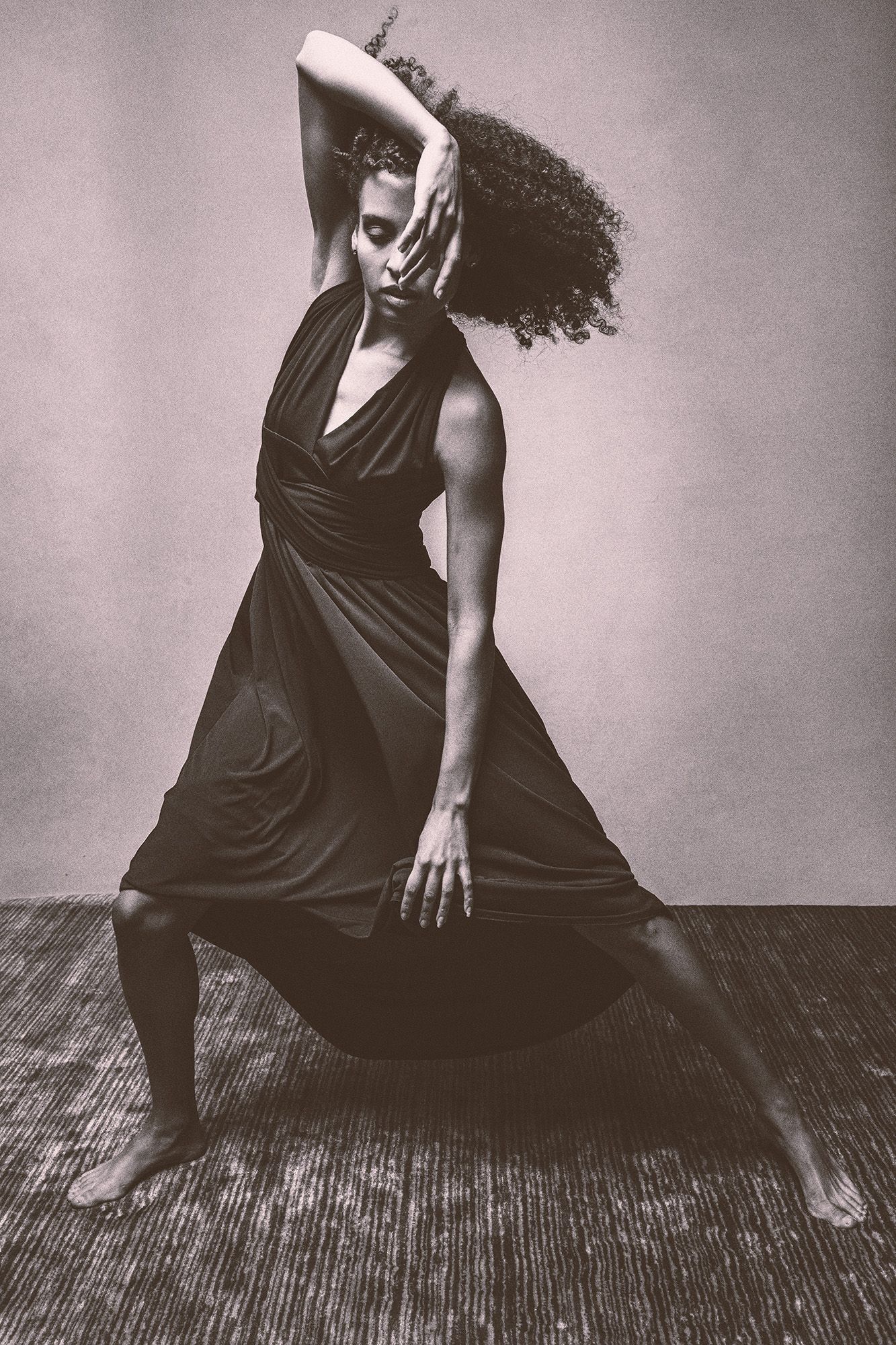 Black and white photo of dancer in flowing black dress mid-movement.
