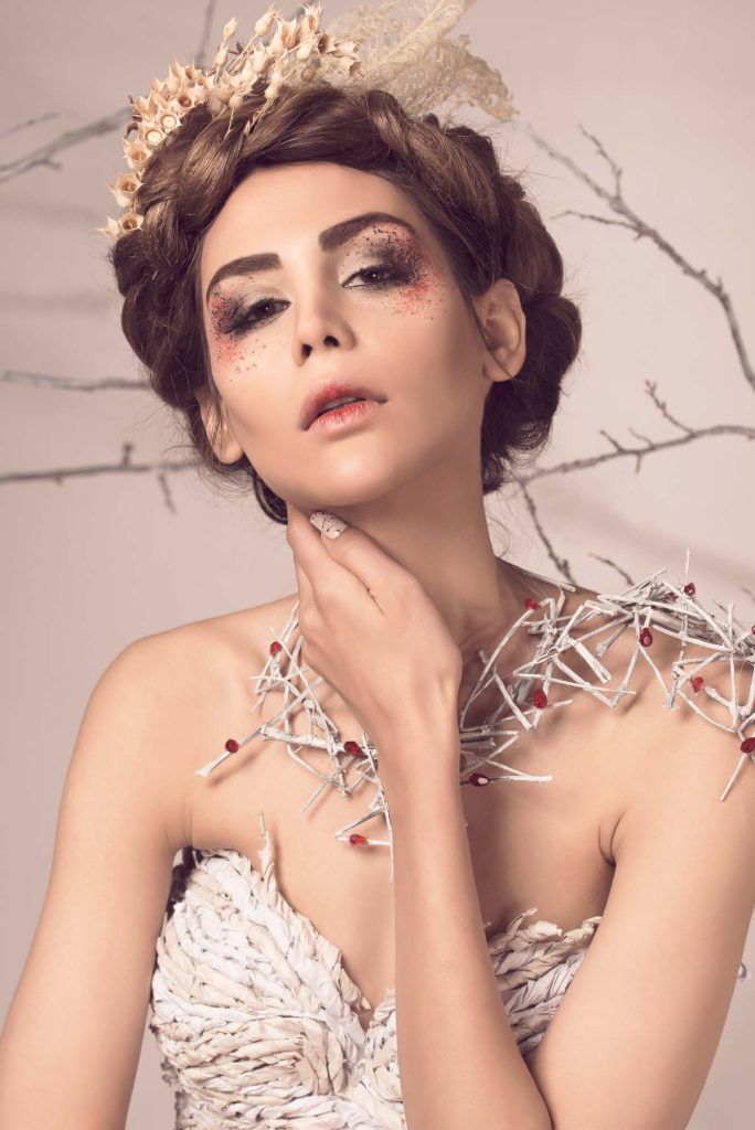 Woman with ornate crown headpiece and avant-garde white twig shoulder piece in beauty editorial.