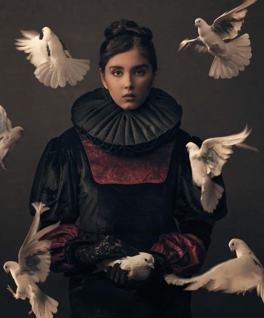 Fine art portrait of a young girl in Renaissance costume surrounded by flying white doves.
