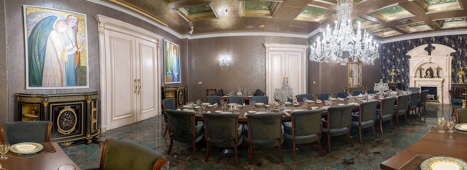 Elegant boardroom with long conference table, chandelier, ornate murals, and green upholstered chairs in a luxurious setting.