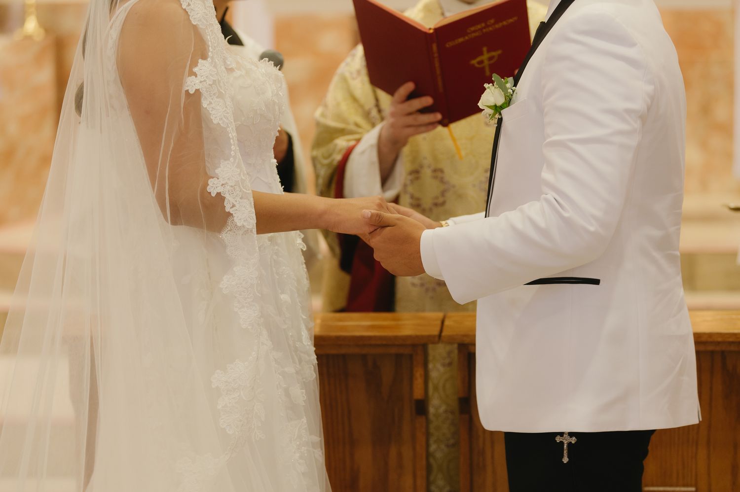 Bride and groom exchange rings during a traditional church wedding ceremony with an officiant in golden robes.