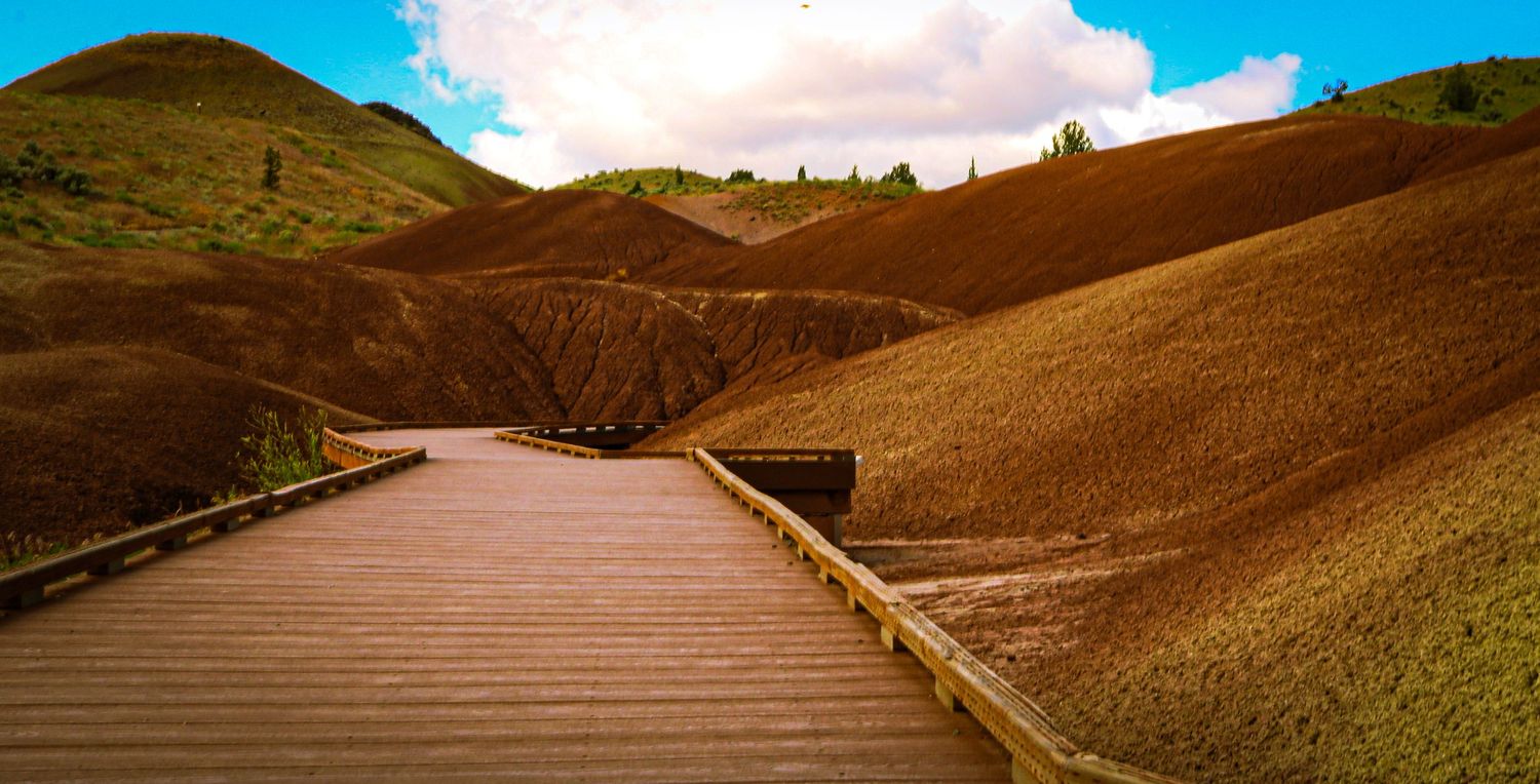Wooden boardwalk trail winding through the colorful painted hills of Oregons John Day Fossil Beds.