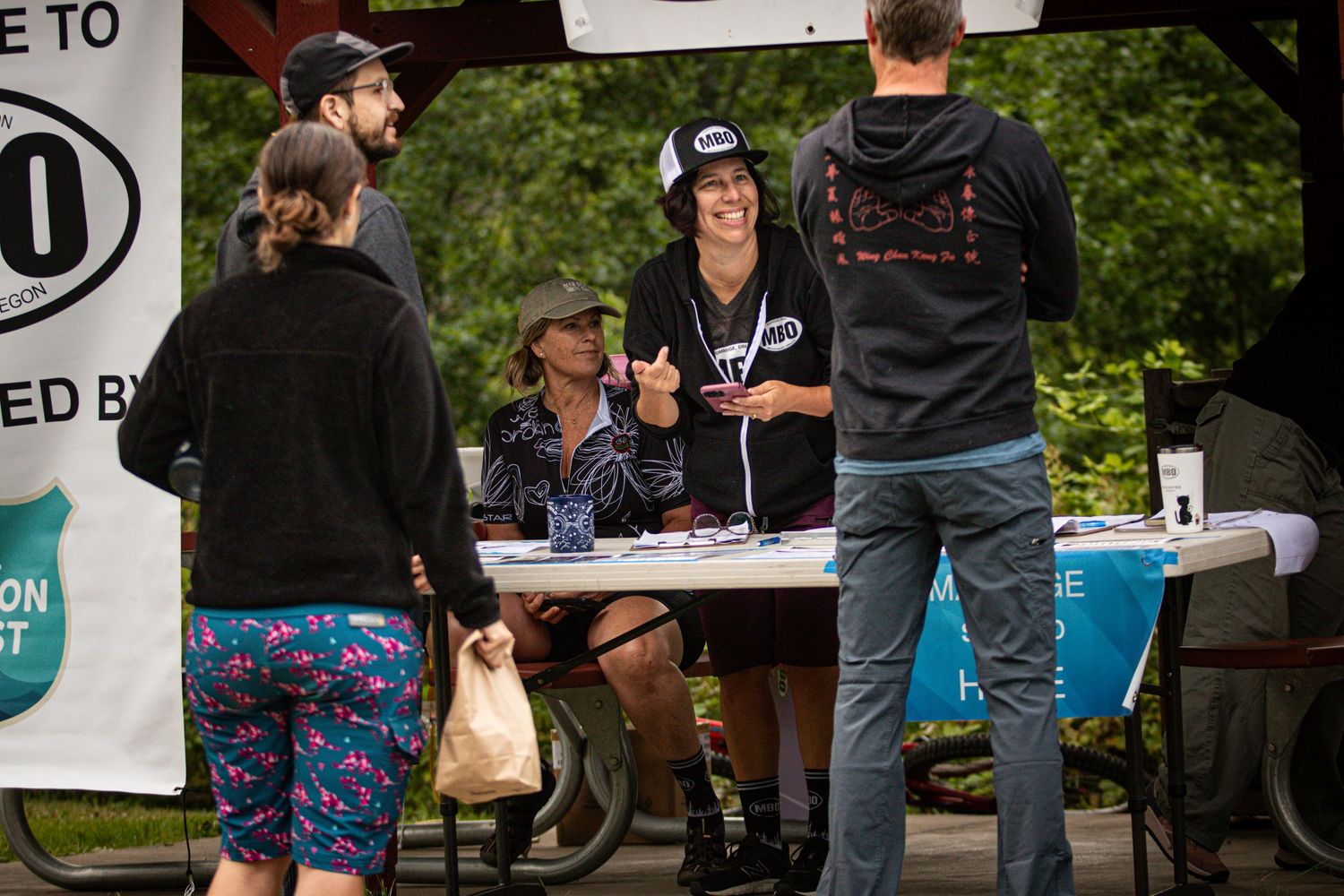 Group of people gathered at an outdoor registration table during a community event in a park.