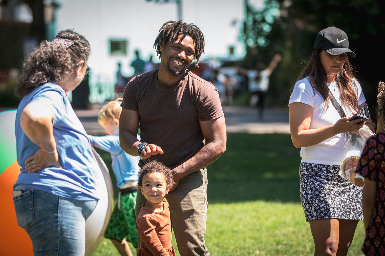 Happy family with young child enjoying an outdoor community park event on sunny day.