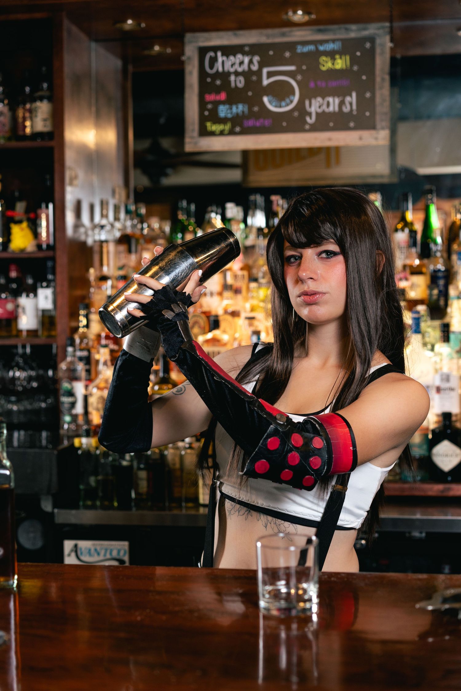 Woman cosplaying as Tifa Lockhart from Final Fantasy VII shaking a cocktail at a bar.