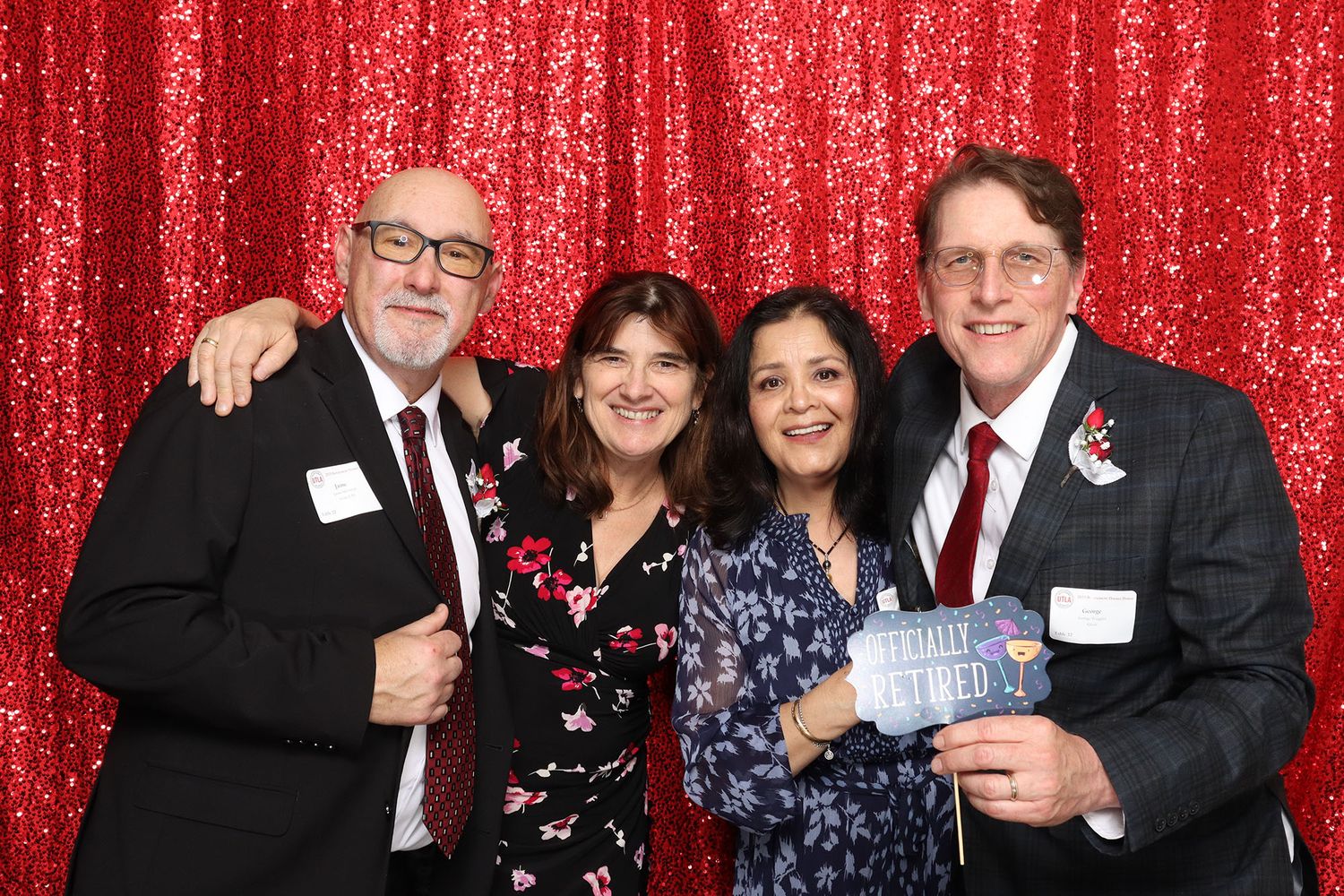Four smiling adults posing together in front of a red sequin backdrop at a formal event.