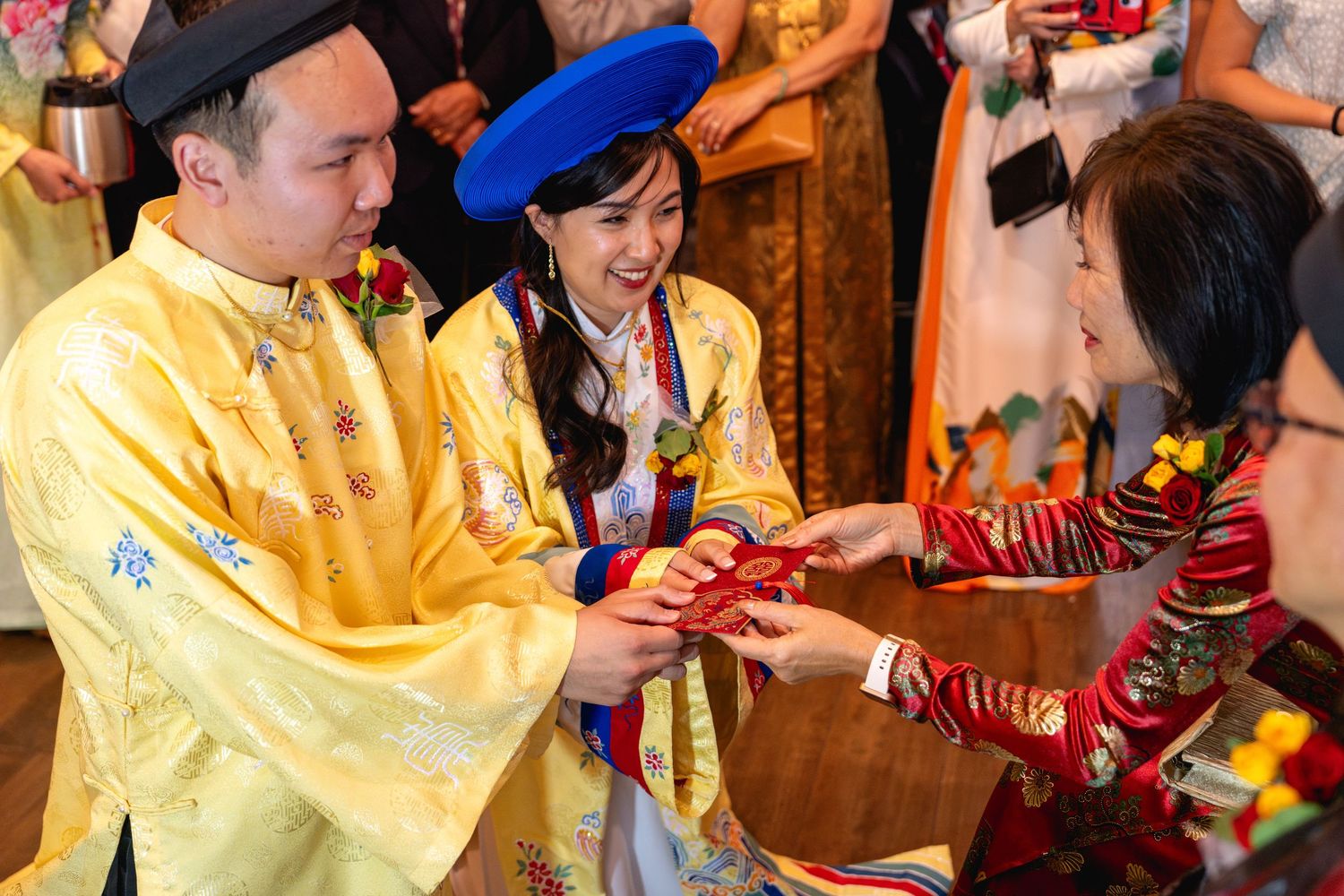Couple in Vietnamese traditional ao dai attire exchange gifts during wedding ceremony.