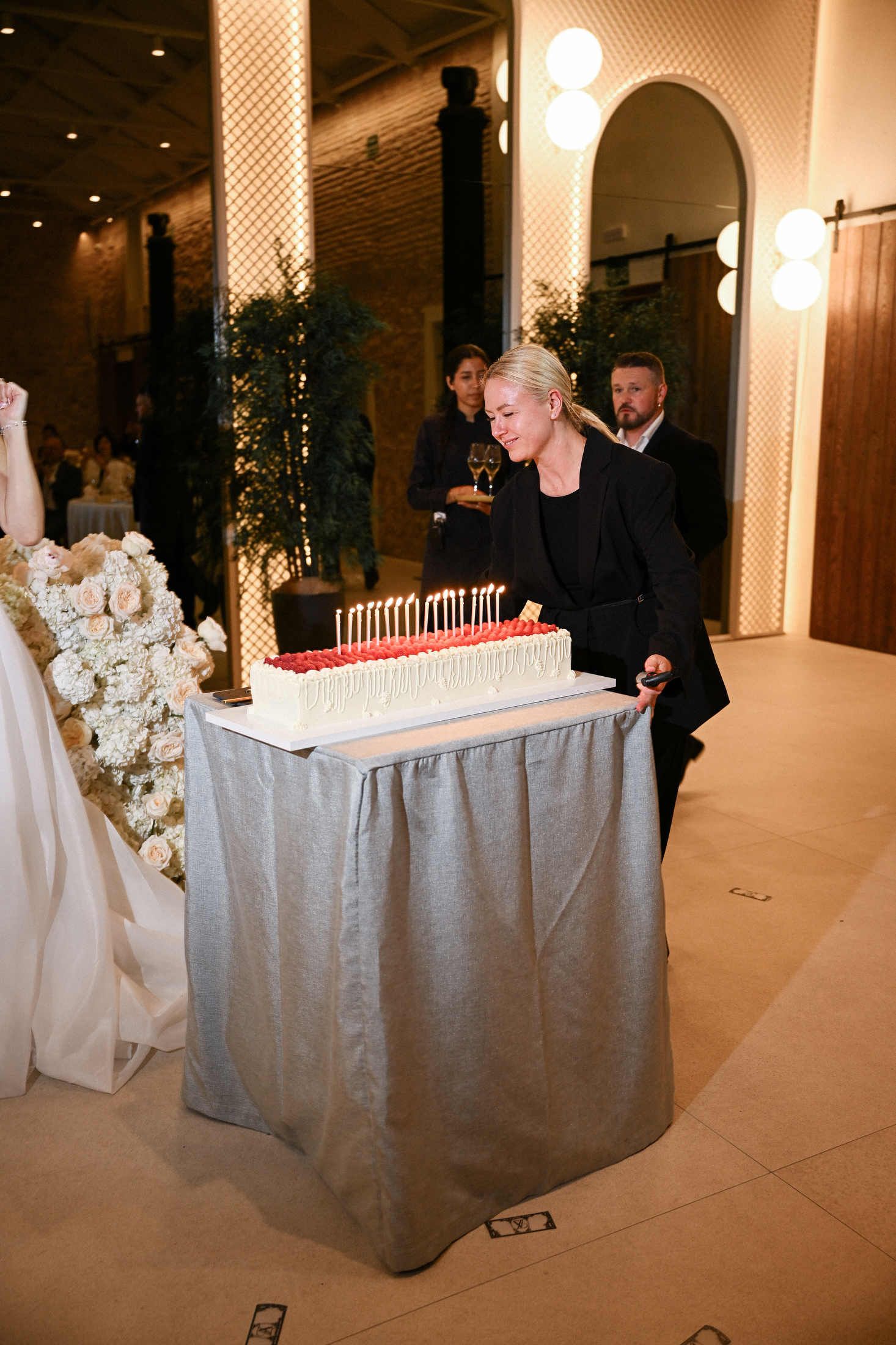Wedding planner Olga Prudko preparing a beautiful long cake with fresh raspberries and candles for the couple's reception in finca canonigo.