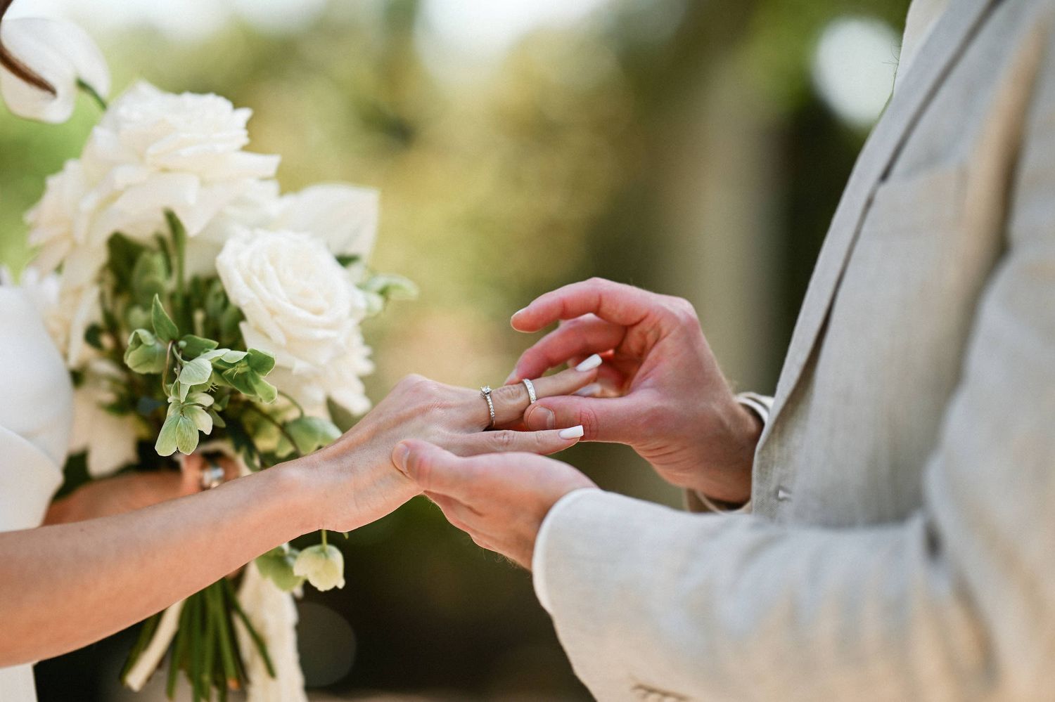 Close-up of a groom placing a wedding ring on the bride's finger during their outdoor destination wedding in Valencia.