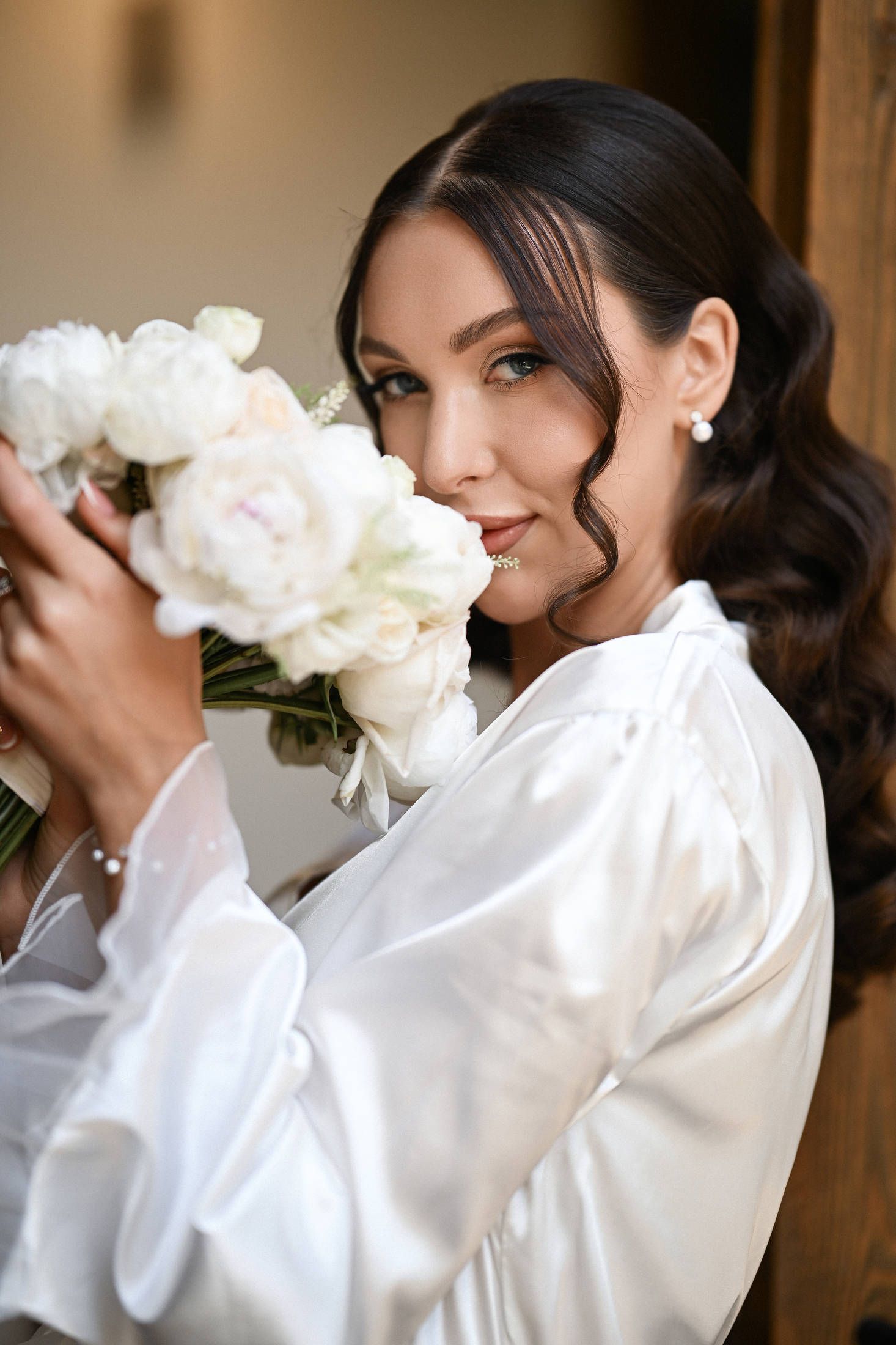 Beautiful bride holding a white bouquet near her face during her wedding day at Finca del Canónigo in Valencia.