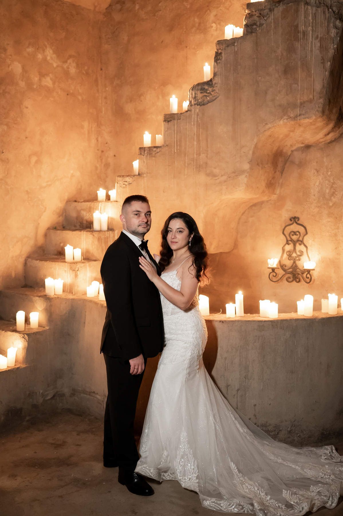 Bride and groom posing by stone stairs decorated with glowing candles during a wedding photoshoot at Casa Santonja.