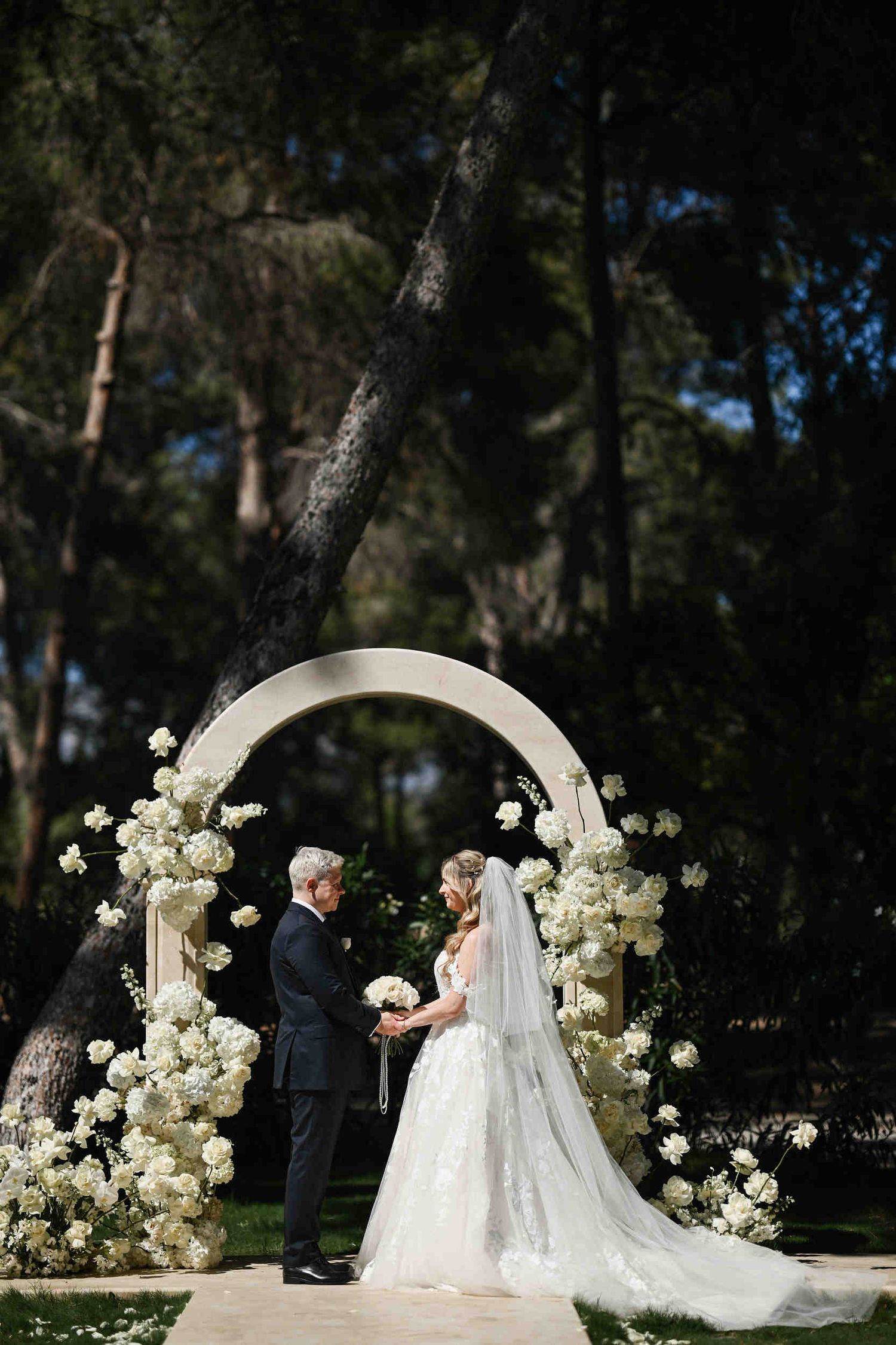 Bride and groom under a floral stone archway during a pine forest wedding in Benidorm, organized by an expert planner.