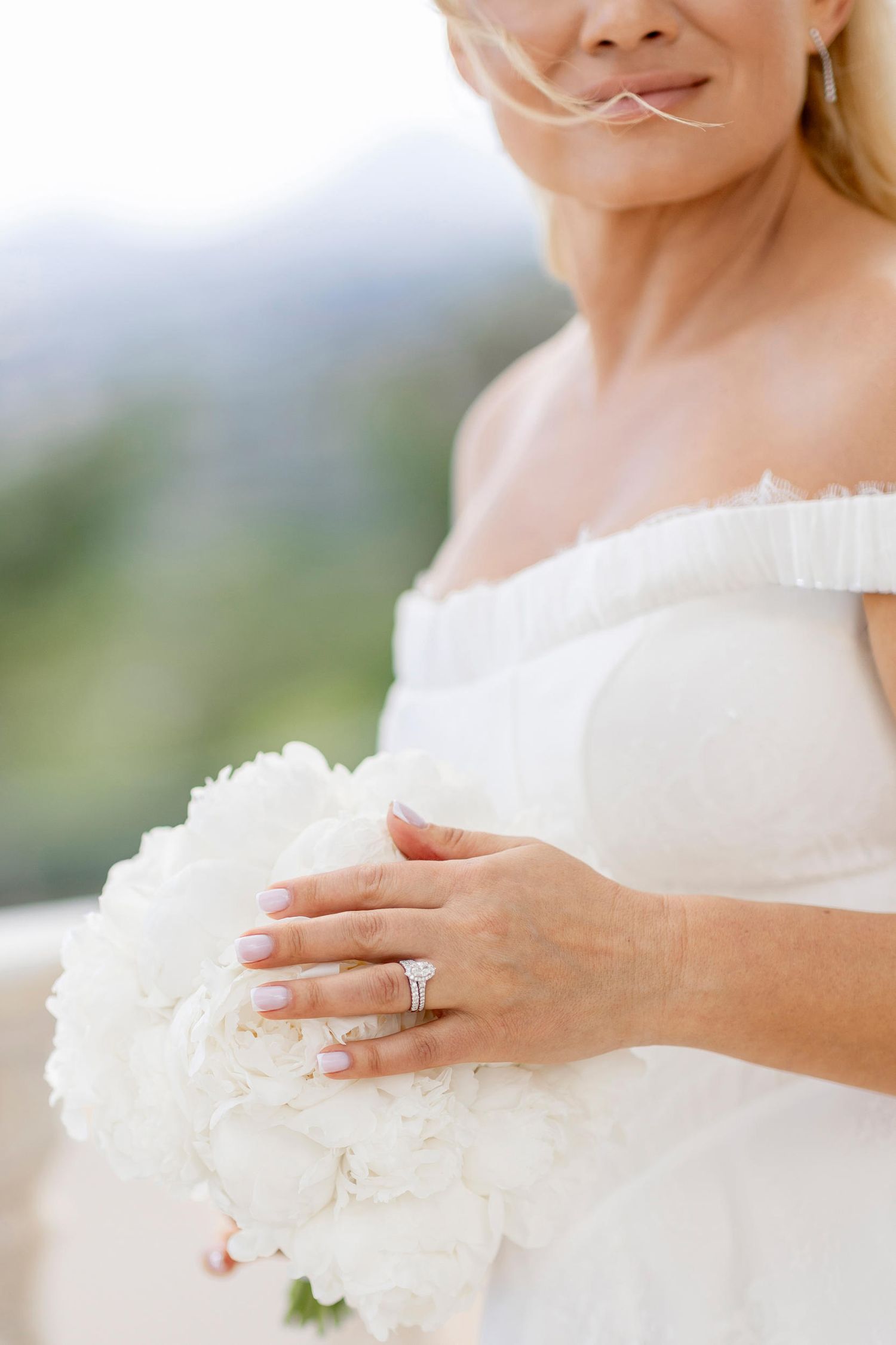 Close-up of a bride showing her sparkling engagement ring while holding a white rose bouquet at her wedding in Spain.