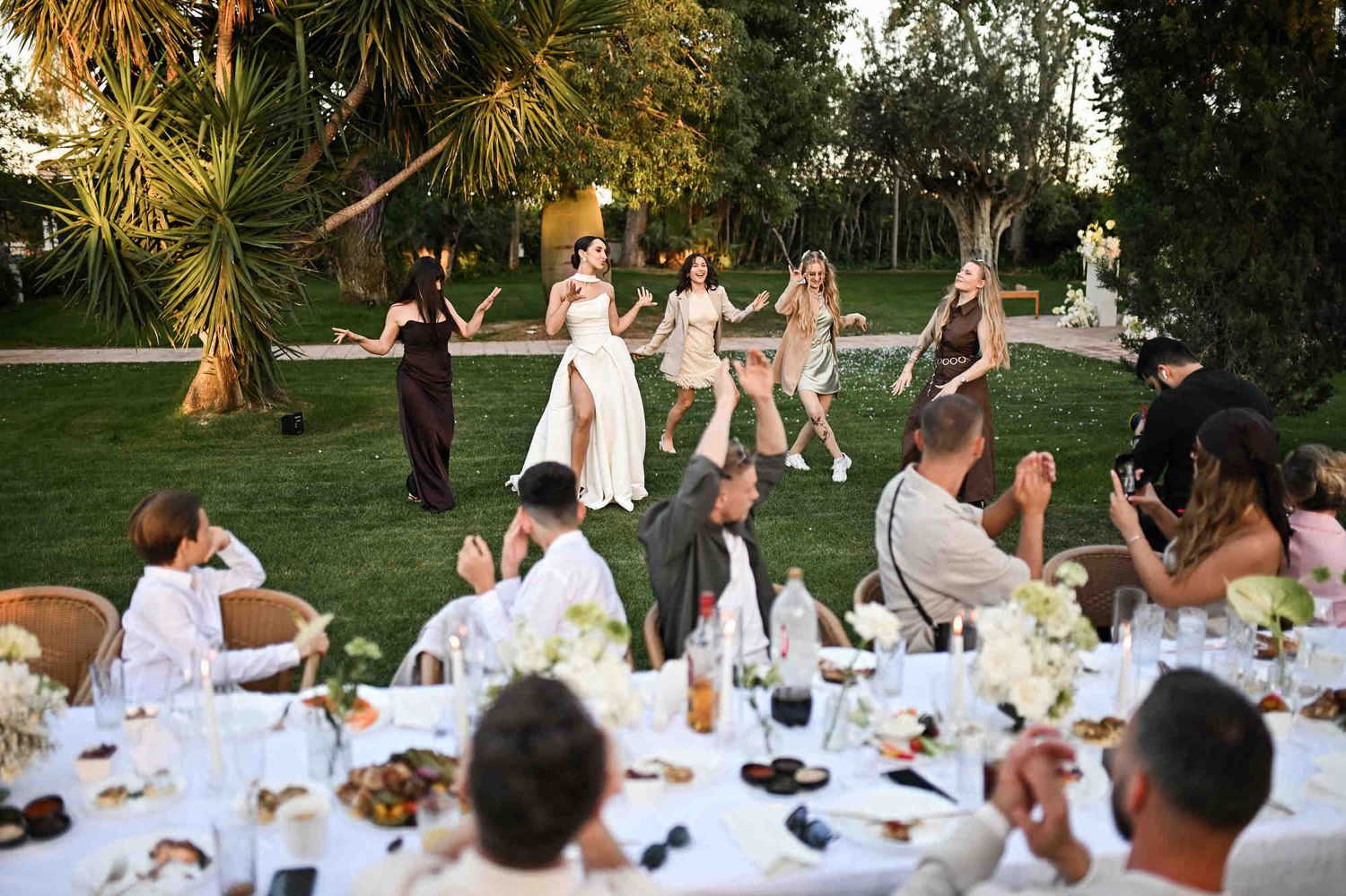 Bride and bridesmaids dancing barefoot on the lawn during a joyful outdoor wedding reception at Villa Paula.